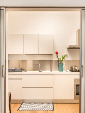 A modern kitchen with a built-in sink, a stove, and a vase with flowers.