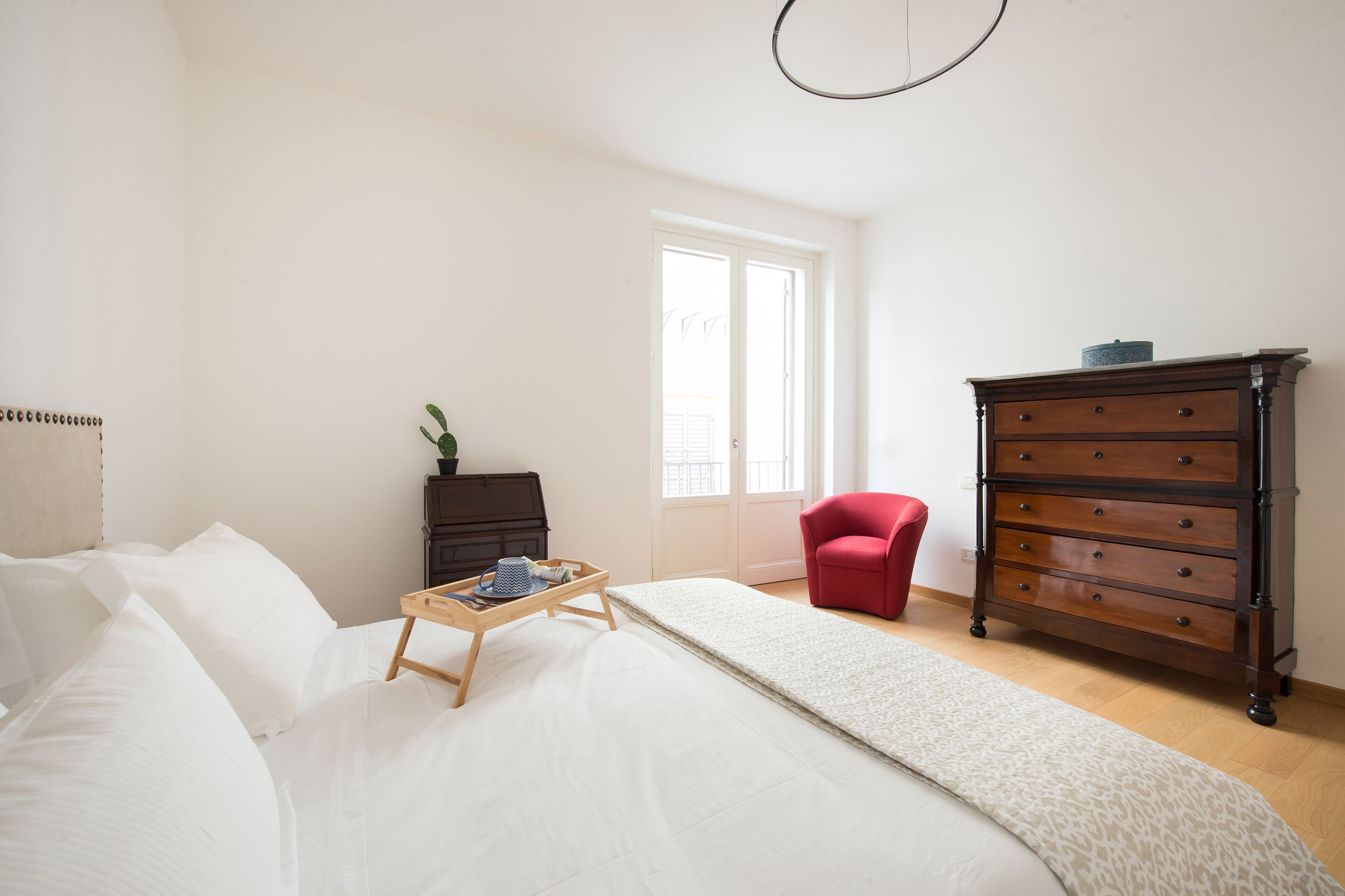 Un dormitorio con cama, cómoda, silla y ventana.