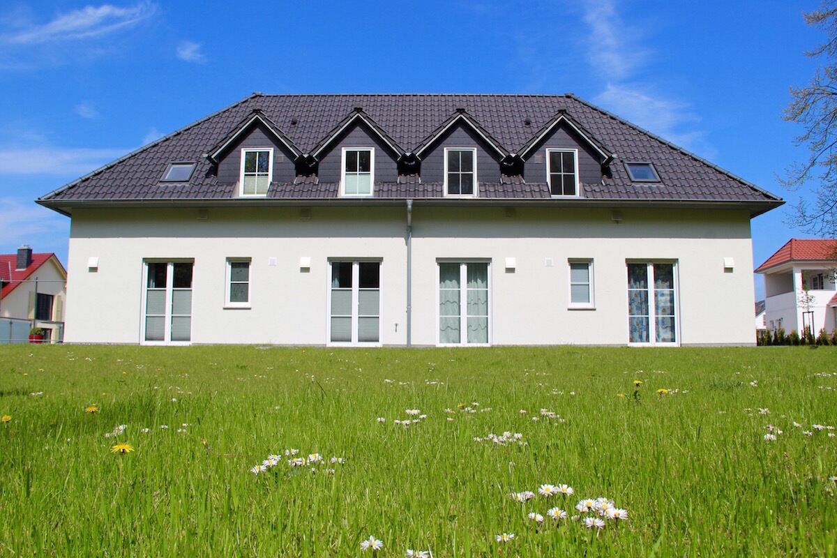 A two-story house with a symmetrical facade, multiple windows, and a sloped roof.