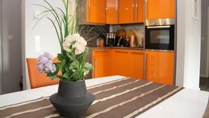 A modern kitchen with orange cabinets and stainless steel appliances. - Haus Sonne (Mönchgut-Granitz)