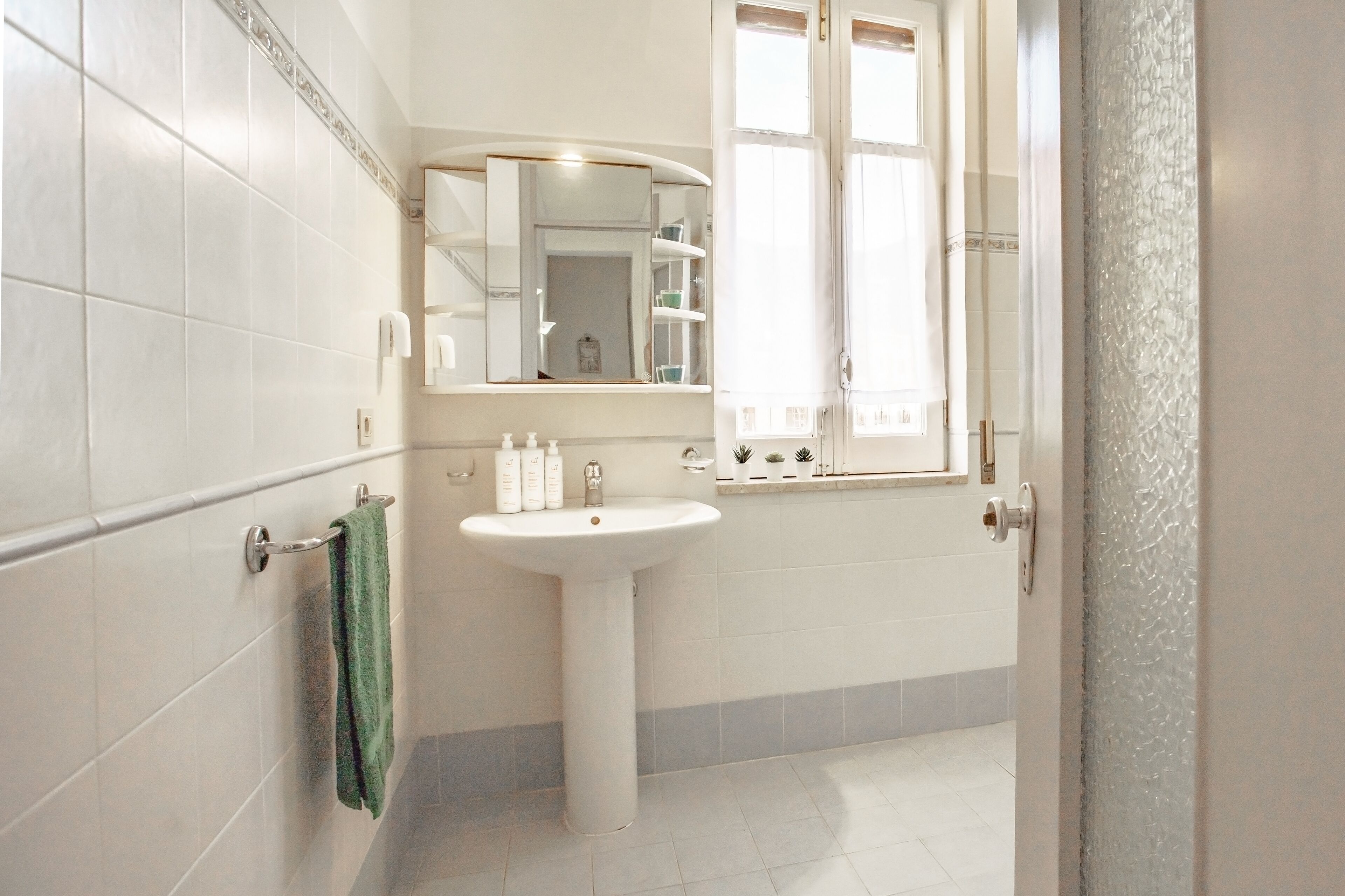 A bathroom with a white sink, a mirror, and a towel rack.