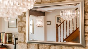 A mirror reflecting a staircase with wooden balusters and a chandelier.