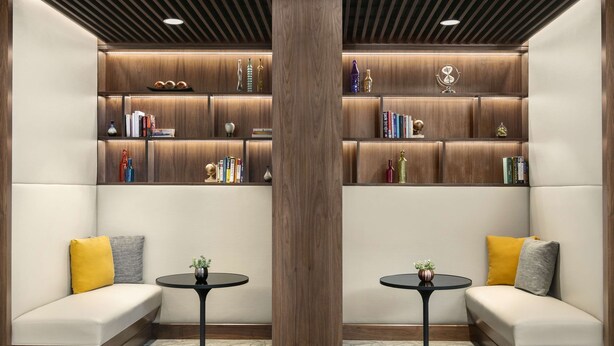 Un interior moderno con una estantería de madera, dos sofás y dos mesas redondas.