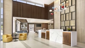 Un moderno vestíbulo de hotel con mostrador de recepción, zona de estar y ventanas amplias.