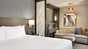 Una habitación de hotel con una cama grande, un sofá, un escritorio y un espejo.