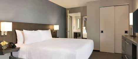 A hotel room with a large bed, bedside lamps, a desk with a phone, and a mirror.