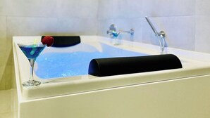 Una bañera con una copa de cóctel azul y un objeto negro en el borde.