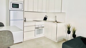 Una cocina moderna con armarios blancos, microondas integrado, estufa y fregadero.
