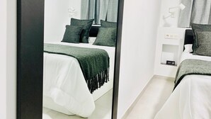 Un dormitorio moderno con una cama, mesitas de noche y un espejo.