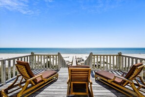 A wooden deck with lounge chairs facing a beach. - You will most assuredly feel SERENDIPTY when you enter this breathtaking beachfront home! (Eastpoint)