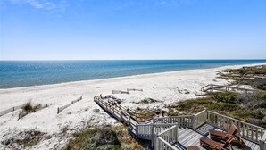 Une vue sur la plage avec une terrasse en bois et des chaises longues.