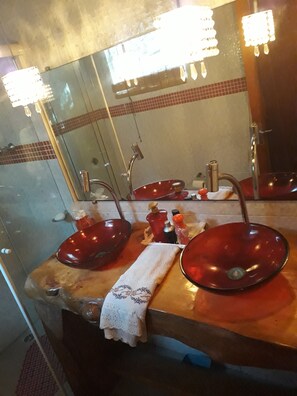 A bathroom with a wooden vanity, two red sinks, a mirror, and a towel. - Cabana da Valentina com Espaço Gourmet (Campos do Jordão)