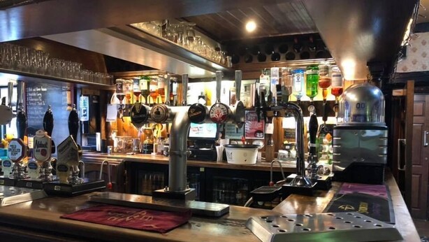 Eine Bar mit mehreren Zapfhähnen, einer Kaffeemaschine und verschiedenen Flaschen.