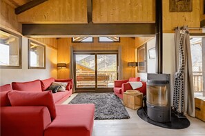 Uma sala de estar acolhedora com sofás vermelhos, lareira e vista para um deck de madeira.
