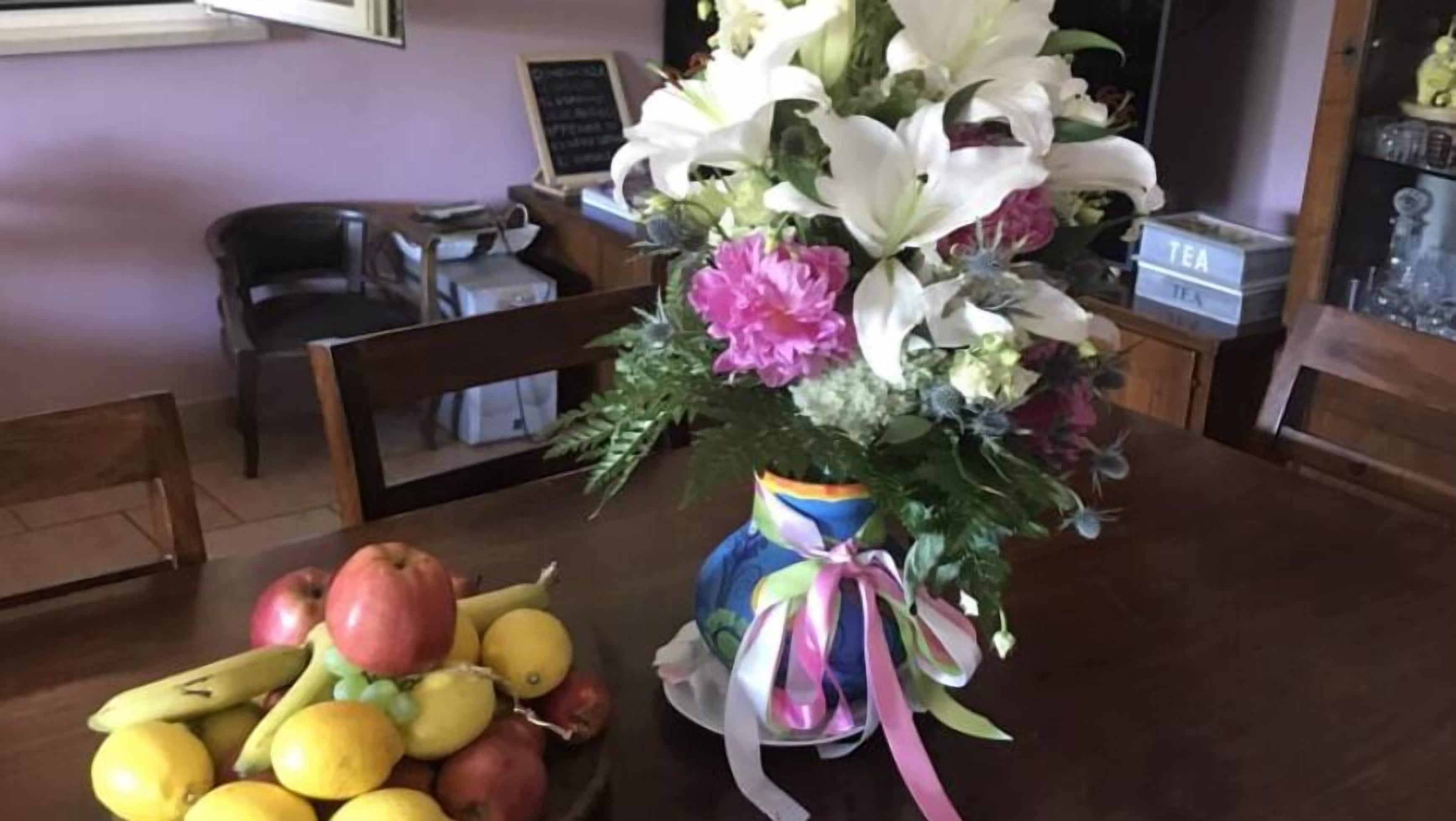 A dining table with a fruit bowl and a vase of flowers.