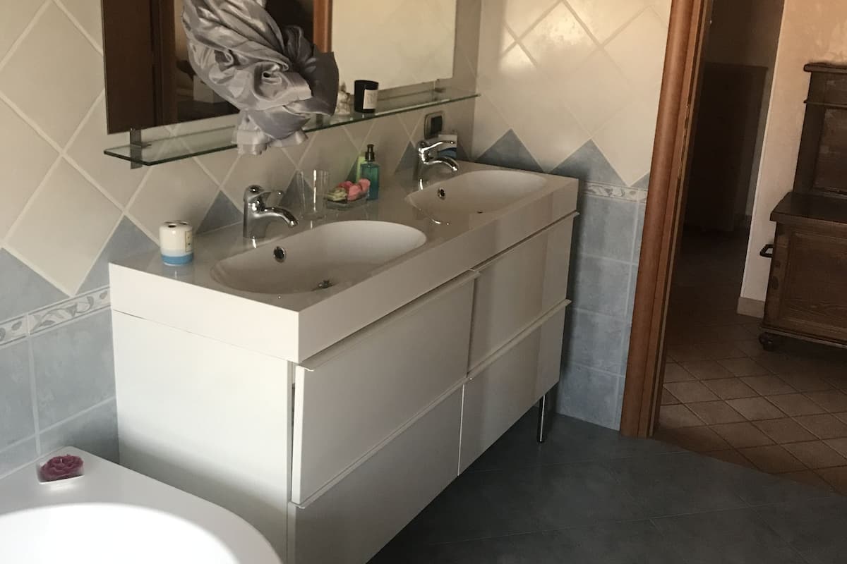 A bathroom with a double sink, a large mirror, and a bathtub.