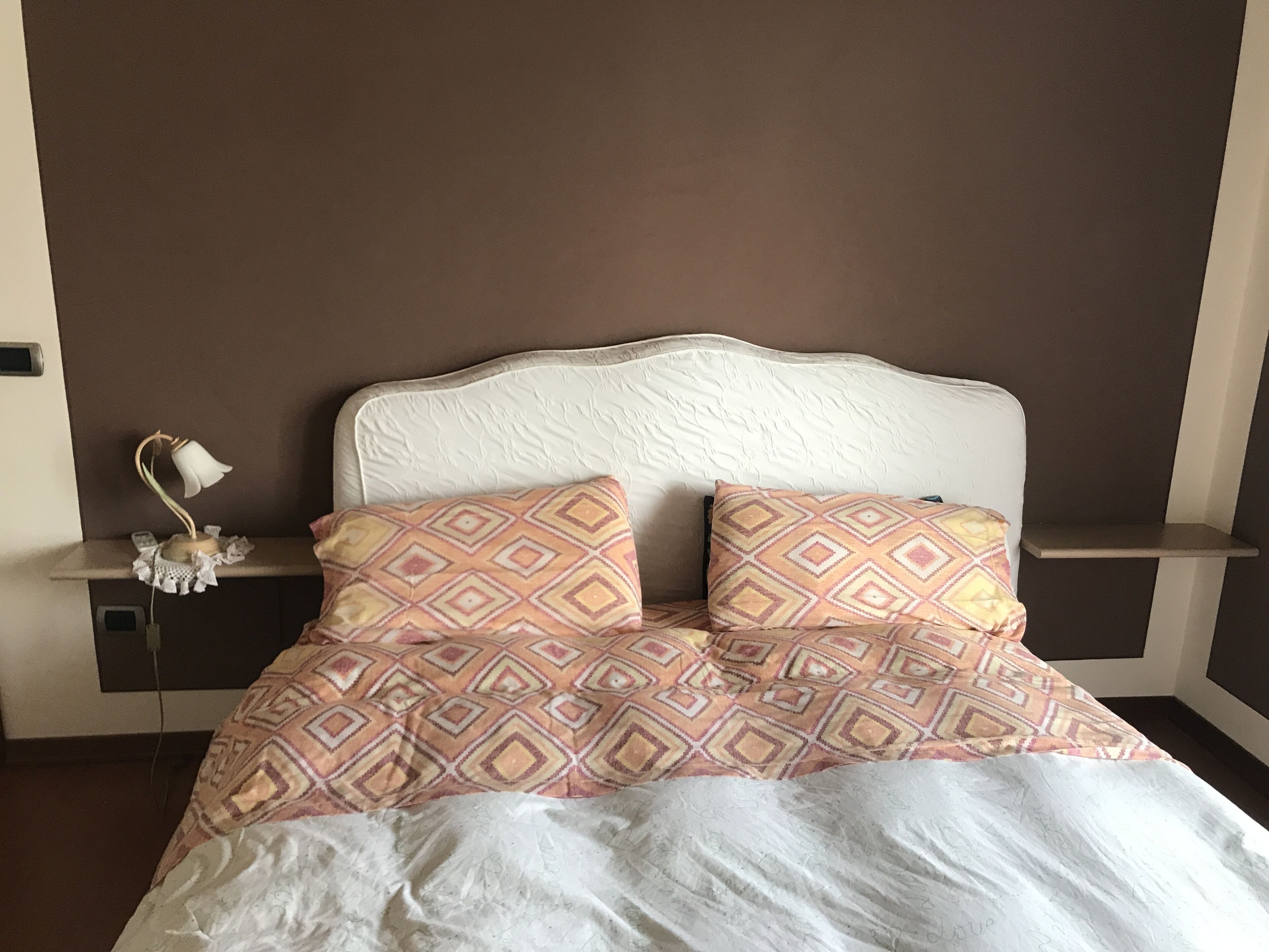 Una cama bien hecha con almohadas estampadas y un cabecero blanco.