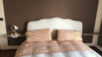 Una cama bien hecha con almohadas estampadas y un cabecero blanco.