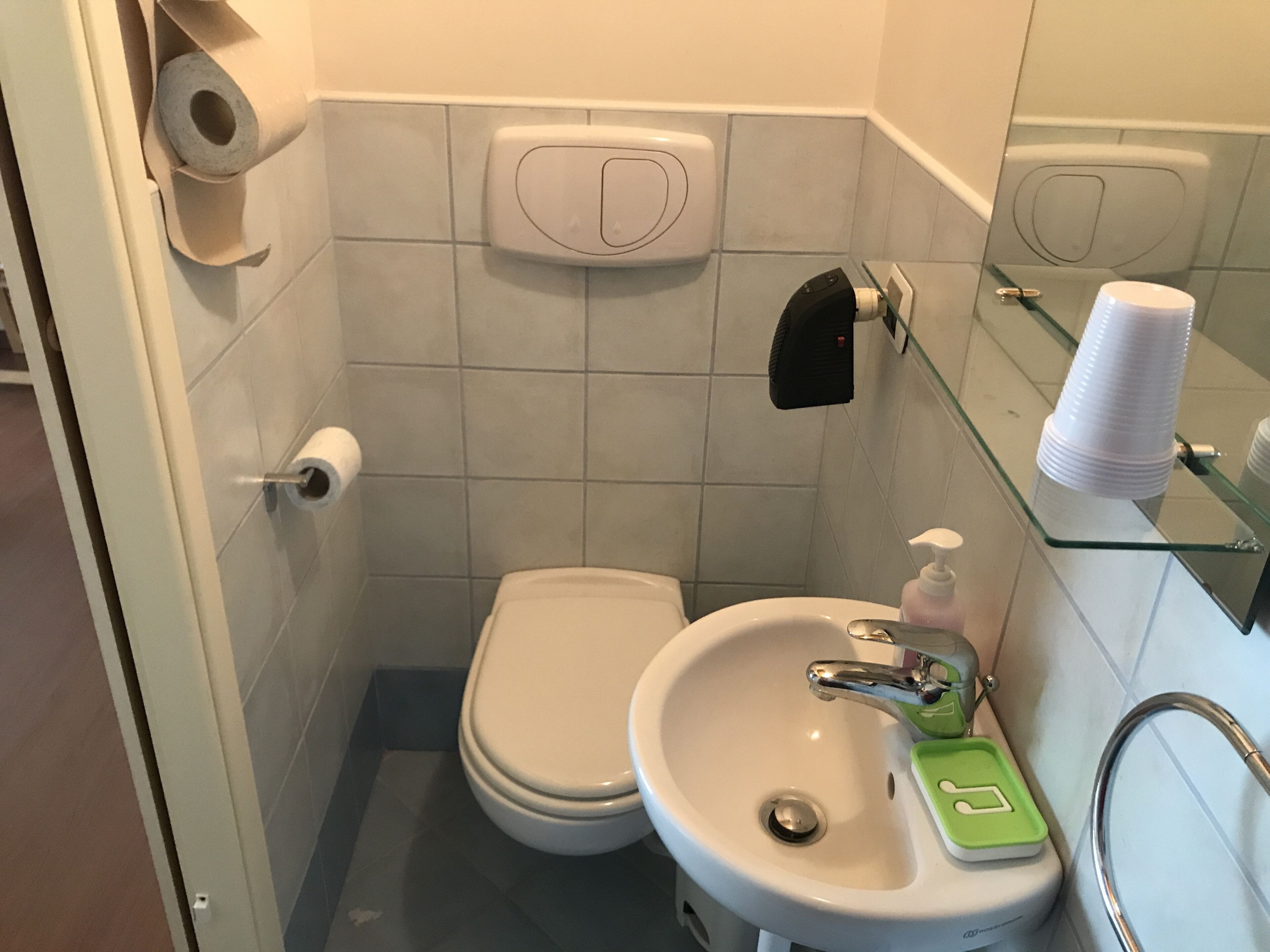 A bathroom with a toilet, sink, and glass shower enclosure.