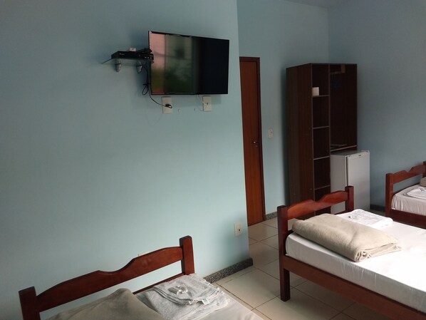 A bedroom with a bed, a TV mounted on the wall, a wardrobe, and a door. - Hotel Pousada do Sol (Uba)