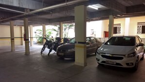 A parking garage with concrete pillars, a white car, and a motorcycle. - Hotel Pousada do Sol (Uba)
