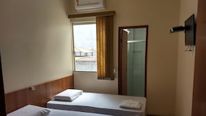 A hotel room with two beds, a window with curtains, a TV mounted on the wall, and a door leading to a bathroom. - Hotel Pousada do Sol (Uba)