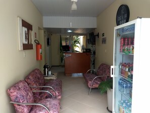 A reception area with two patterned chairs, a refrigerator stocked with beverages, and a clock on the wall. - Hotel Pousada do Sol (Uba)