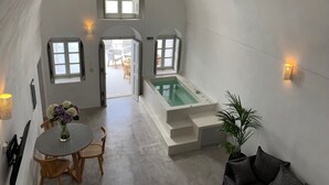 Une pièce spacieuse avec une grande baignoire, un coin repas avec une table et des chaises, et une plante en pot.