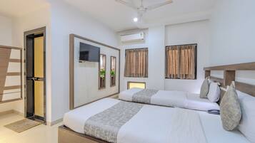 Habitación de hotel con dos camas, ventilador de techo, unidad de aire acondicionado y puerta con espejo.