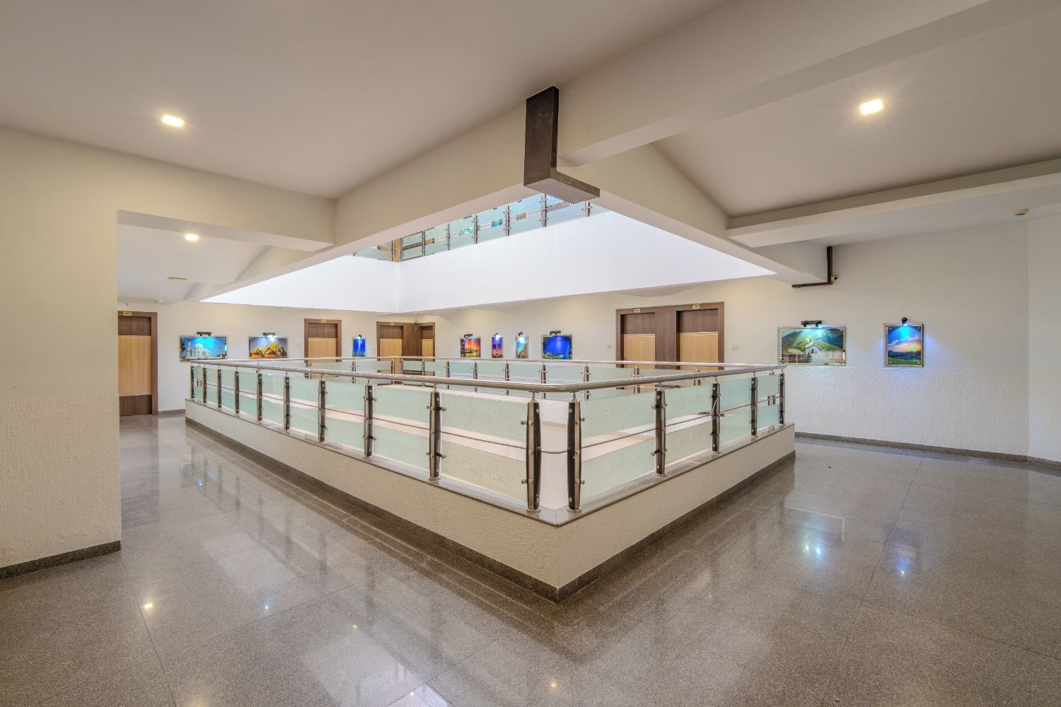 A spacious hotel lobby with a central glass railing, a high ceiling, and a modern design.