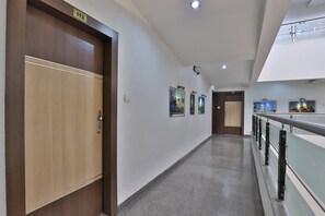 Un couloir avec une porte en bois portant le numéro « 113 », un plancher ciré et une rambarde ornée d’éléments décoratifs.
