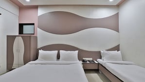 A hotel room with a large bed, two bedside tables, a wardrobe, and a decorative wall panel. - Hotel Merit (Surat)