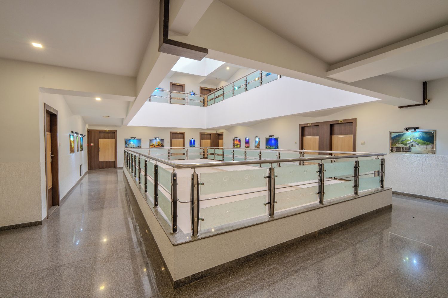 A spacious hotel lobby with a glass railing, a mezzanine level, and artwork on the walls.