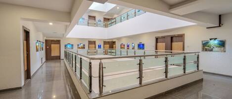 A spacious hotel lobby with a glass railing, a mezzanine level, and artwork on the walls.