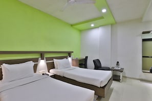 A hotel room with two beds, a desk, a chair, and a mirror.
