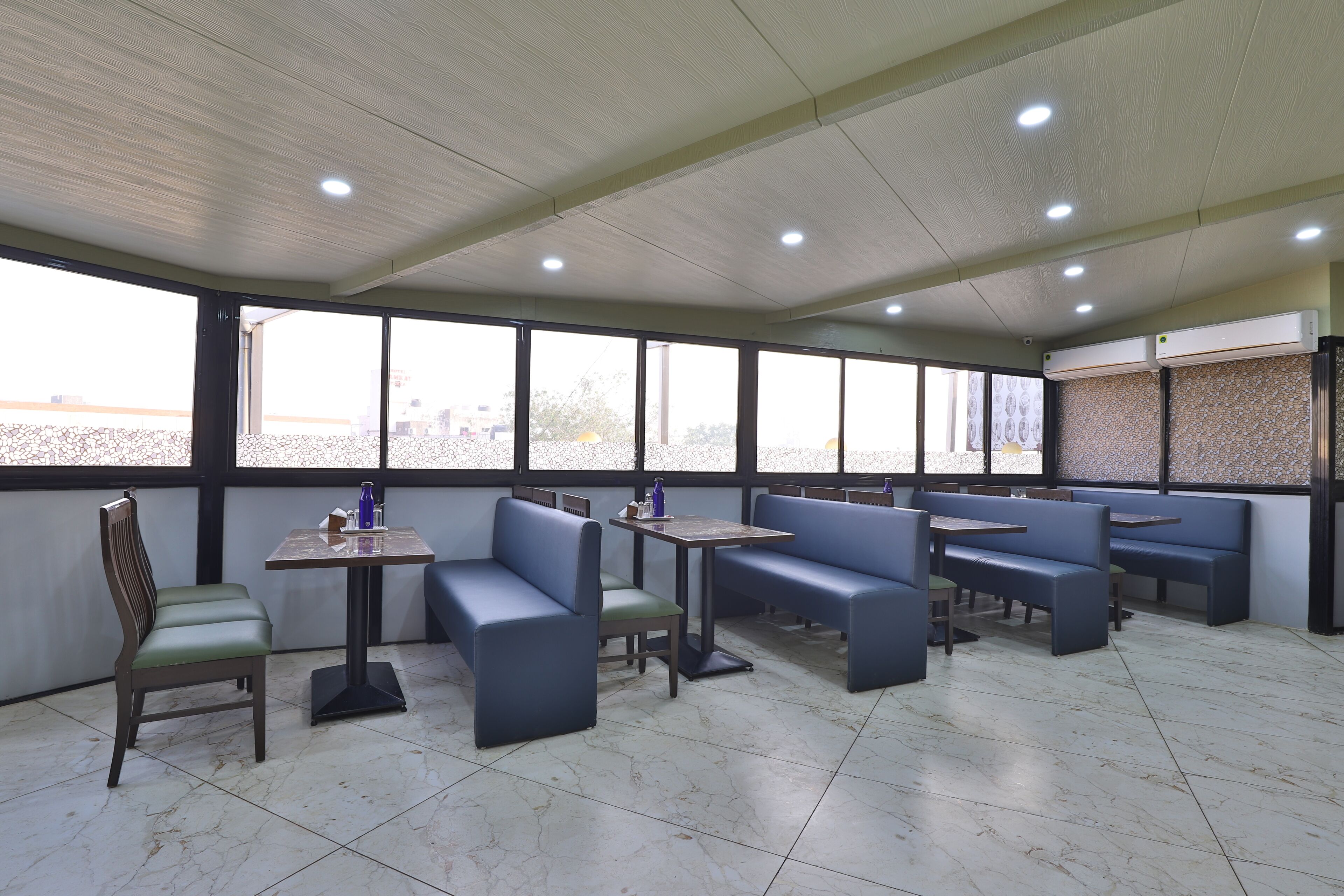 A spacious indoor seating area with high ceilings, large windows, and a tiled floor. - Hotel Merit (Surat)