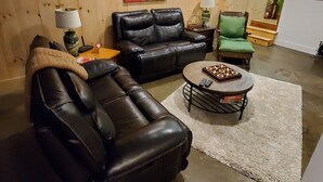 Un salon avec un canapé en cuir noir, un fauteuil assorti et une table basse.
