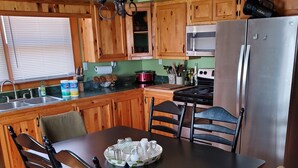 Une cuisine avec des meubles en bois, un réfrigérateur en acier inoxydable et une table à manger avec des chaises.