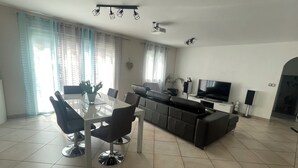A modern living room with a glass dining table, black chairs, a grey sofa, a flat-screen TV, and a ceiling projector. - Modern air-conditioned villa in a quiet location with swimming pool between Cassis and La Ciotat (Roquefort-la-Bédoule)