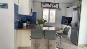 A modern kitchen with a wooden island, bar stools, a stainless steel refrigerator, and a clock on the wall. - Modern air-conditioned villa in a quiet location with swimming pool between Cassis and La Ciotat (Roquefort-la-Bédoule)