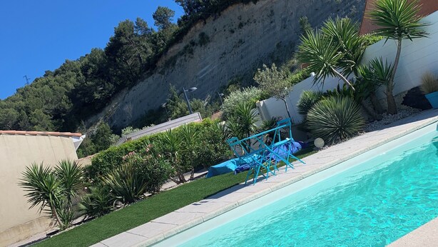 A swimming pool with clear water, surrounded by greenery and a hillside. - Modern air-conditioned villa in a quiet location with swimming pool between Cassis and La Ciotat (Roquefort-la-Bédoule)