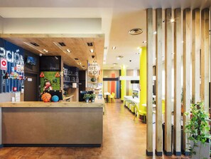 Welcome to our reception area, featuring a central counter, digital screen, and comfortable seating area with a partition.
