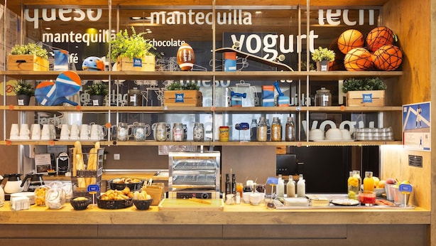 Un mostrador de panadería con diversas opciones de repostería, una exhibición de yogur y una máquina de café.