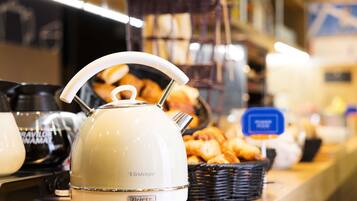 Una cocina con un hervidor de estilo vintage sobre una encimera, una cesta de pasteles y una cafetera.