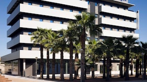 Un hotel moderno de varios pisos con techo plano y un llamativo letrero 'ibis budget'.