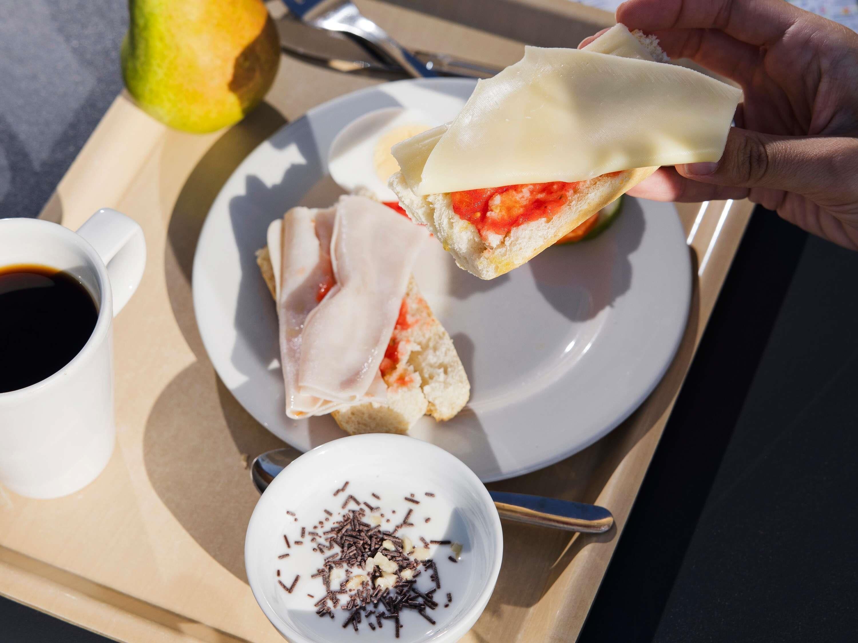 Een dienblad met een belegd broodje, een kop koffie en een klein bakje hagelslag.