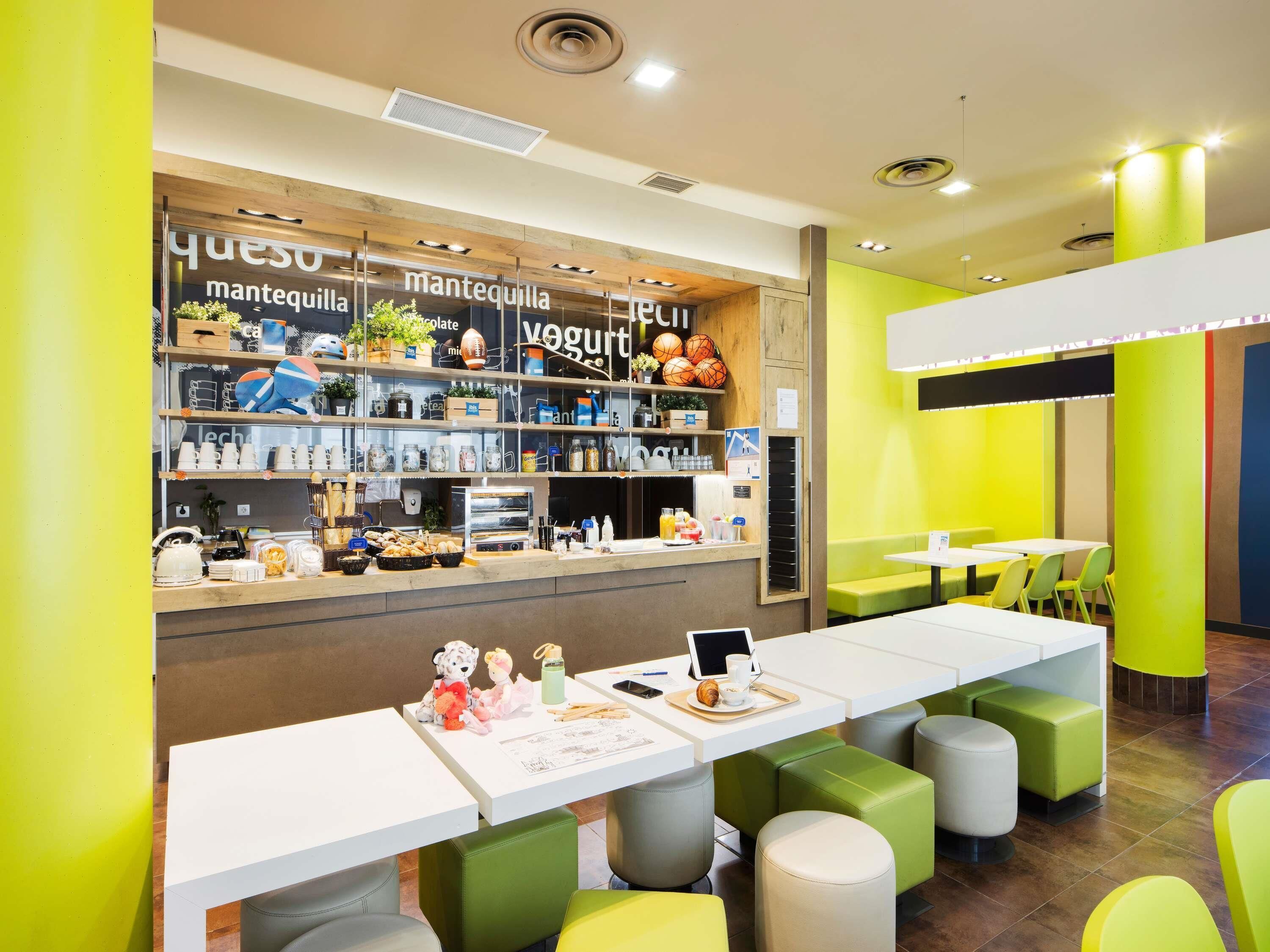 A café with a counter displaying various food items and a seating area with tables and chairs.