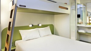 A bunk bed with a green headboard, a bedside table with a bottle, and a mirror above the bed. - ibis budget Oviedo (Oviedo)