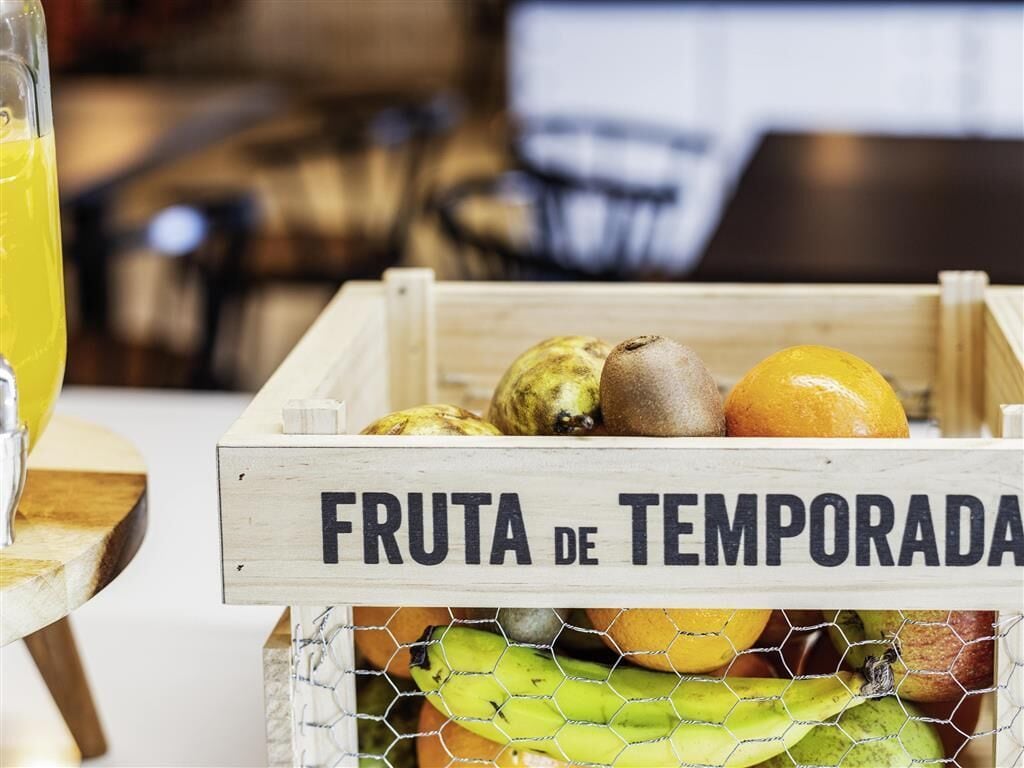 Una caja de madera etiquetada como “FRUTA DE TEMPORADA” con diversas frutas.