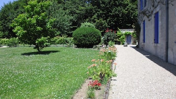 Stroll through the beautifully maintained garden, surrounded by vibrant flowers and a neatly trimmed hedge, leading to the rustic building.